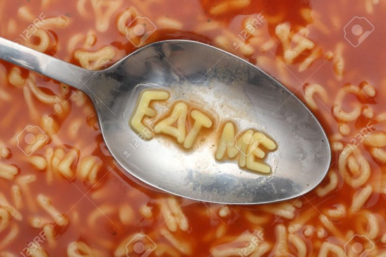 Alphabet letters in spoon spell out "Eat me". Alphabet Soup Pasta. Close-up.